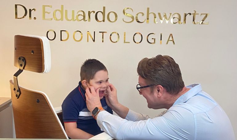 Dr. Eduardo Schwartz avaliando a mordida de uma criança na Schwartz Odontologia.